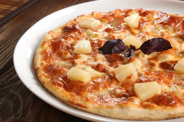 Pizza with pineapple on white plate