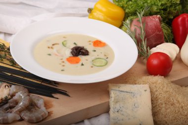 İtalyan sebze çorbası, tahtadan yapılmış taze yiyeceklerle çevrili.