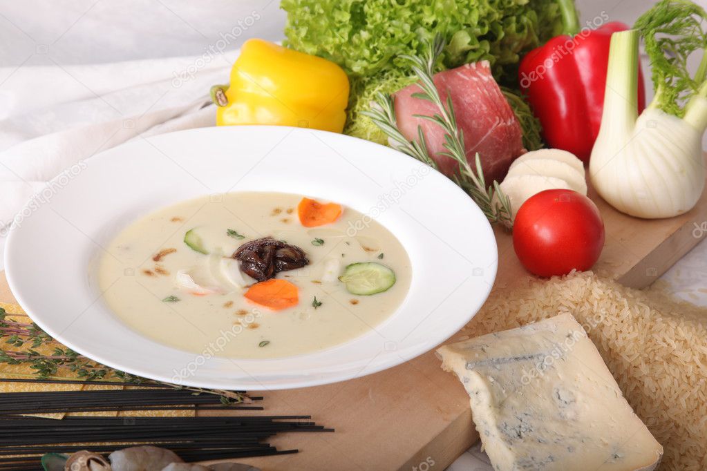 Italian vegetable soup, surrounded by fresh food on wooden board