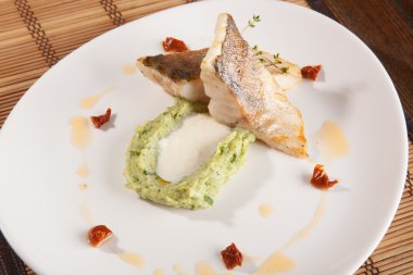 Beyaz tabakta patates püresi ve peynir sosu ile turna balığı.