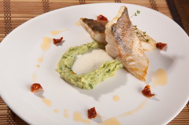 Beyaz tabakta patates püresi ve peynir sosu ile turna balığı.