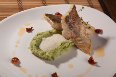 Beyaz tabakta patates püresi ve peynir sosu ile turna balığı.