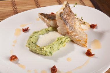 Beyaz tabakta patates püresi ve peynir sosu ile turna balığı.