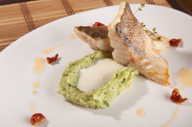 Beyaz tabakta patates püresi ve peynir sosu ile turna balığı.