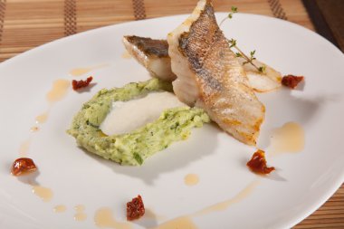 Beyaz tabakta patates püresi ve peynir sosu ile turna balığı.