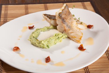 Beyaz tabakta patates püresi ve peynir sosu ile turna balığı.