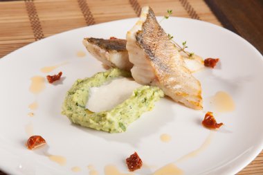 Beyaz tabakta patates püresi ve peynir sosu ile turna balığı.