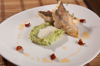 Beyaz tabakta patates püresi ve peynir sosu ile turna balığı.