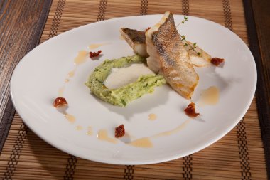 Beyaz tabakta patates püresi ve peynir sosu ile turna balığı.