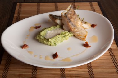 Beyaz tabakta patates püresi ve peynir sosu ile turna balığı.