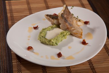 Beyaz tabakta patates püresi ve peynir sosu ile turna balığı.