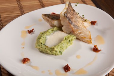 Beyaz tabakta patates püresi ve peynir sosu ile turna balığı.