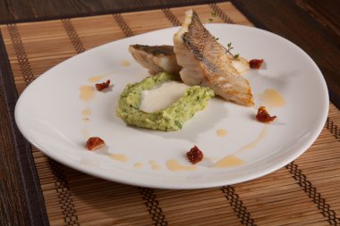 Beyaz tabakta patates püresi ve peynir sosu ile turna balığı.