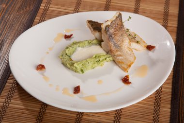 Beyaz tabakta patates püresi ve peynir sosu ile turna balığı.