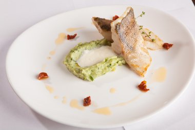 Beyaz tabakta patates püresi ve peynir sosu ile turna balığı.