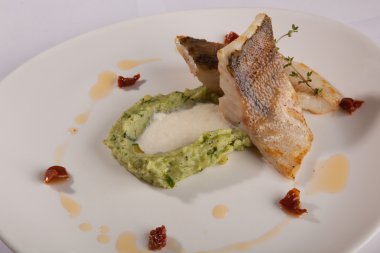 Beyaz tabakta patates püresi ve peynir sosu ile turna balığı.