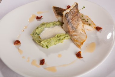 Beyaz tabakta patates püresi ve peynir sosu ile turna balığı.