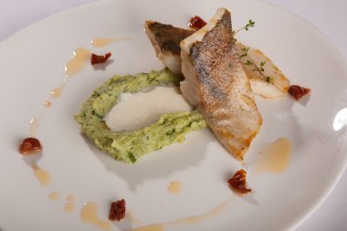 Beyaz tabakta patates püresi ve peynir sosu ile turna balığı.