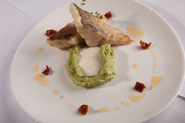 Beyaz tabakta patates püresi ve peynir sosu ile turna balığı.