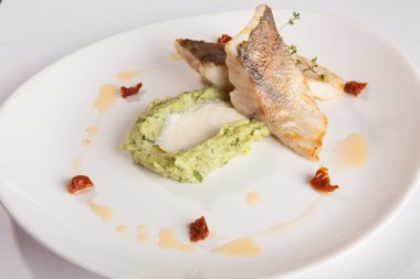 Beyaz tabakta patates püresi ve peynir sosu ile turna balığı.