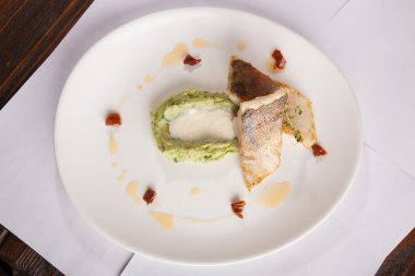 Beyaz tabakta patates püresi ve peynir sosu ile turna balığı.