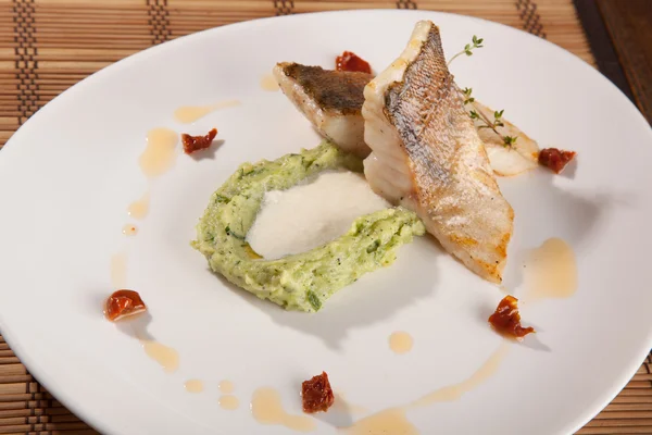 Beyaz tabakta patates püresi ve peynir sosu ile turna balığı.