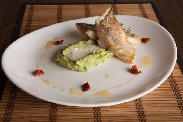 Beyaz tabakta patates püresi ve peynir sosu ile turna balığı.