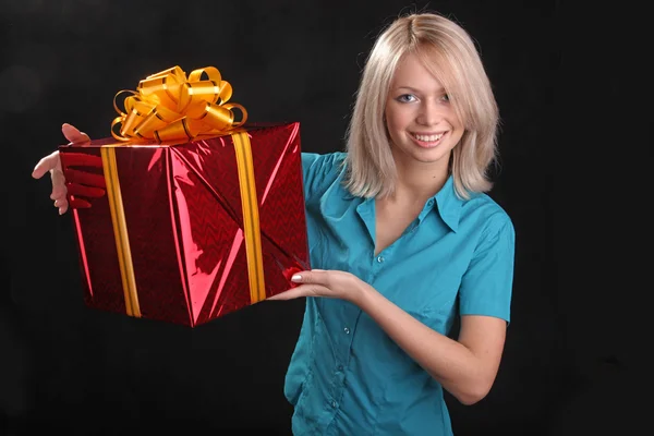 the girl in the blue shirt with a gift in the hands on black background