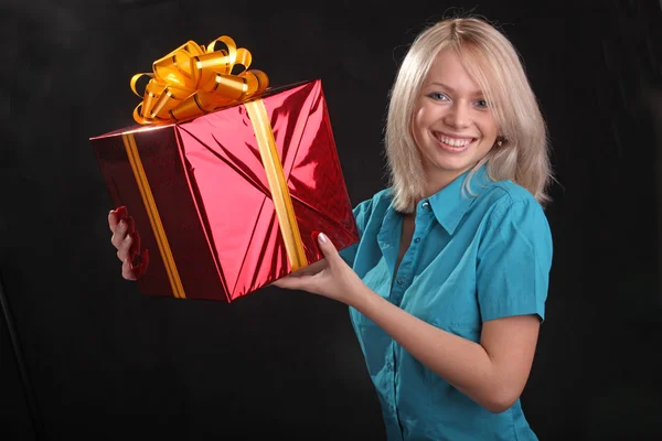 the girl in the blue shirt with a gift in the hands on black background