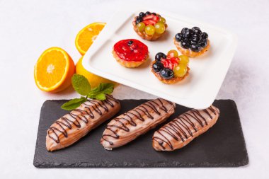 Beyaz arka planda meyveli ve kremalı tatlılar