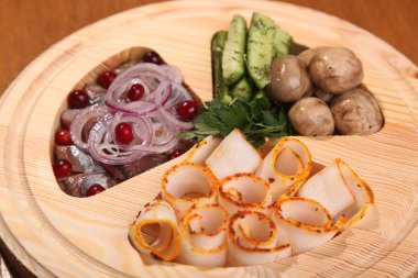 Pastırma ve ringa, ahşap tabakta ve masada.