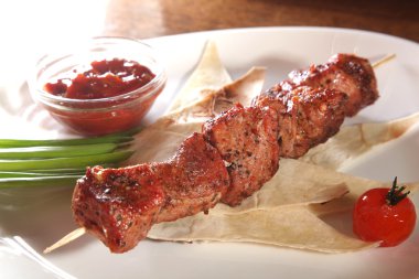 Bir parça ekmek ve tabakta sos şiş.