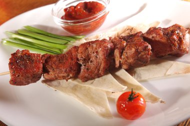 Bir parça ekmek ve tabakta sos şiş.