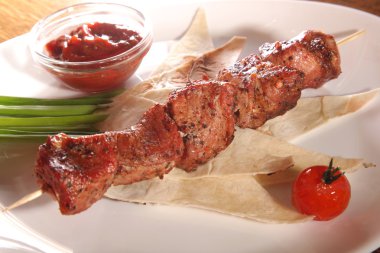 Bir parça ekmek ve tabakta sos şiş.