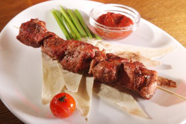 Bir parça ekmek ve tabakta sos şiş.