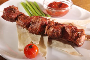 Bir parça ekmek ve tabakta sos şiş.