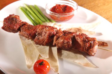 Bir parça ekmek ve tabakta sos şiş.