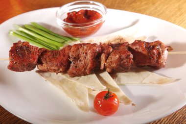 Bir parça ekmek ve tabakta sos şiş.