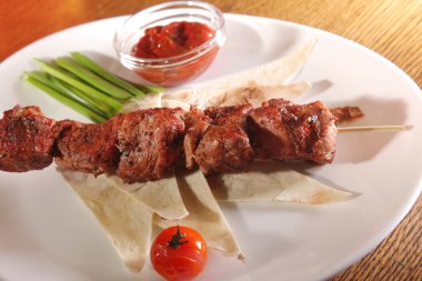 Bir parça ekmek ve tabakta sos şiş.