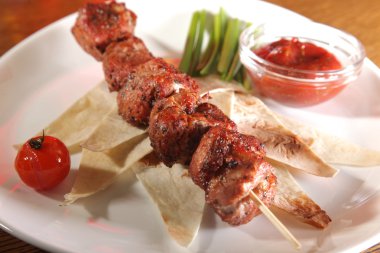 Bir parça ekmek ve tabakta sos şiş.