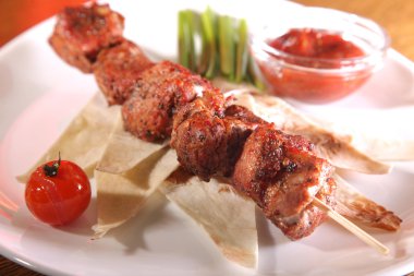 Bir parça ekmek ve tabakta sos şiş.