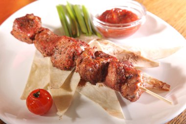 Bir parça ekmek ve tabakta sos şiş.