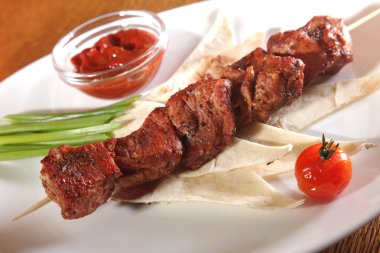 Bir parça ekmek ve tabakta sos şiş.