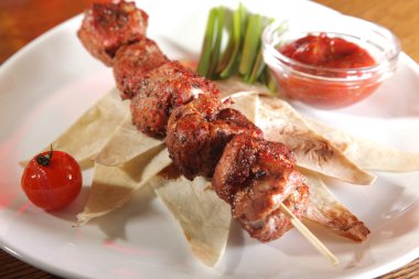 Bir parça ekmek ve tabakta sos şiş.