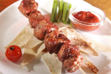 Bir parça ekmek ve tabakta sos şiş.