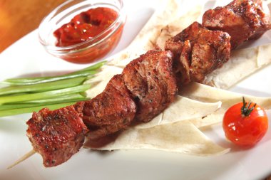 Bir parça ekmek ve tabakta sos şiş.