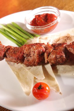 Bir parça ekmek ve tabakta sos şiş.