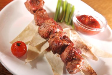 Bir parça ekmek ve tabakta sos şiş.