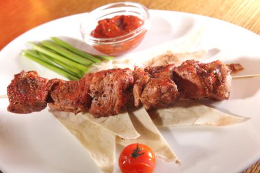 Bir parça ekmek ve tabakta sos şiş.