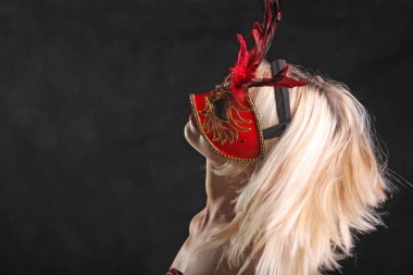 Siyah arka planda güzel bir boynu olan maskeli bir sarışın.